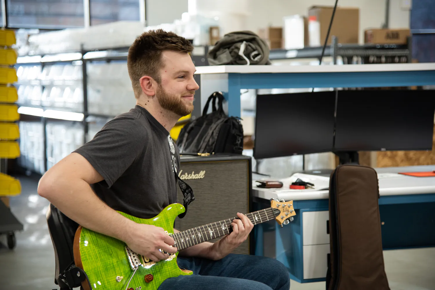 Evan DeVore sitting and playing guitar.