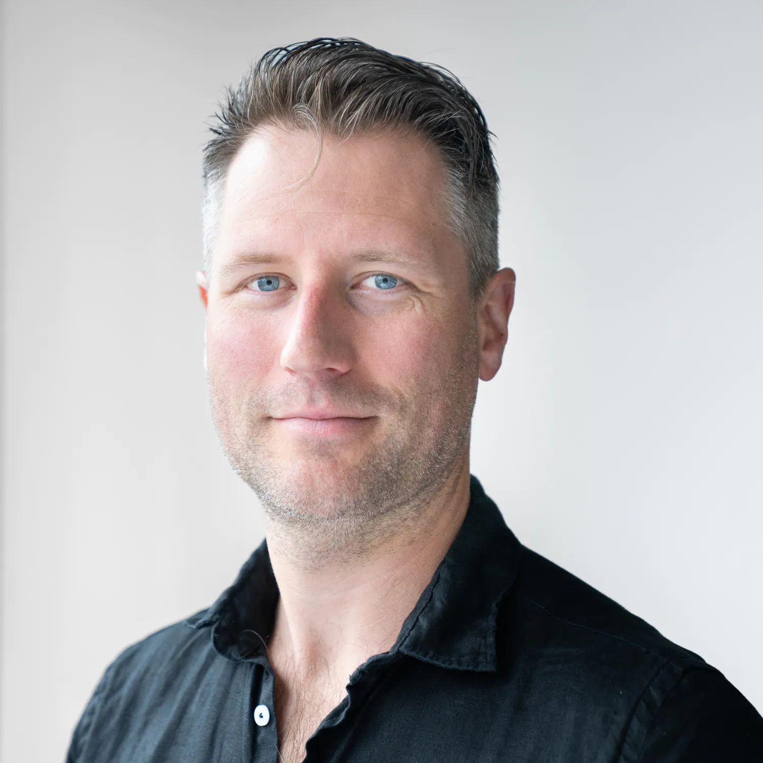 Man with short dark hair, wearing black polo shirt
